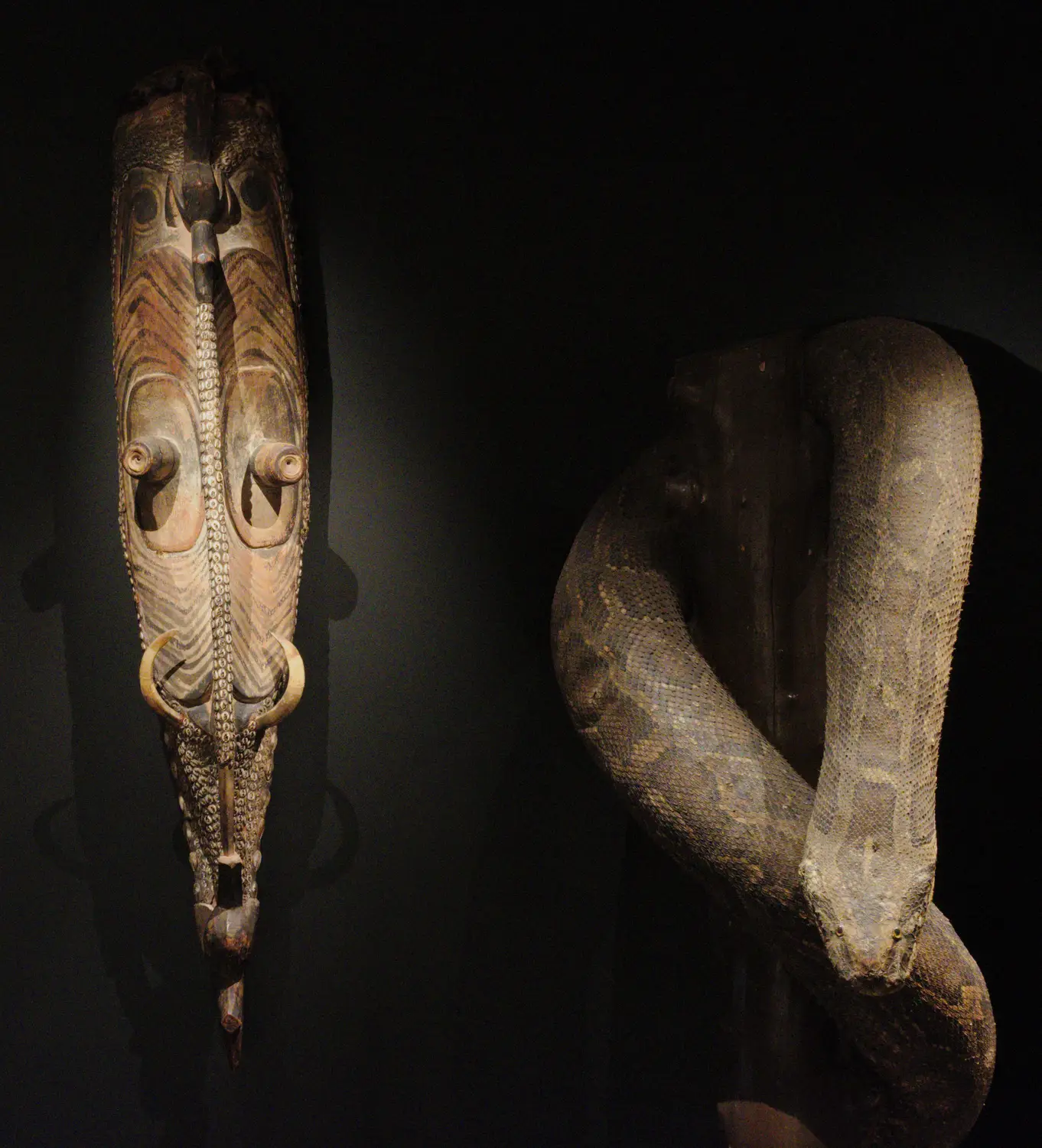 a mask statue and snake statue side by side