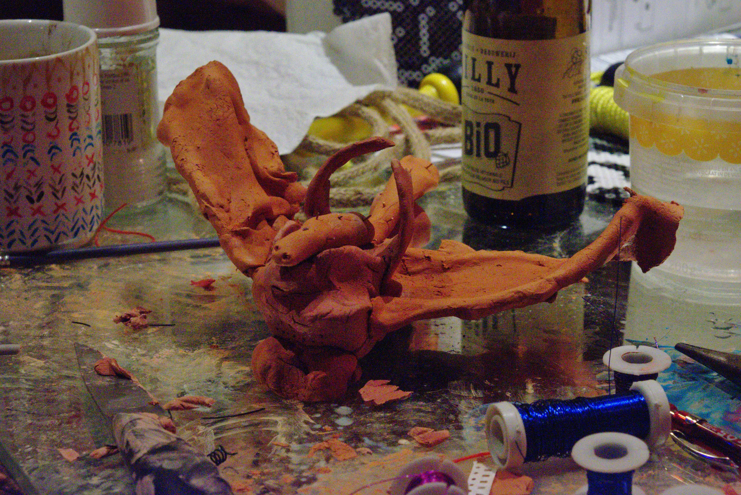 a claycreature on a table surrounded by arts and crafts tools