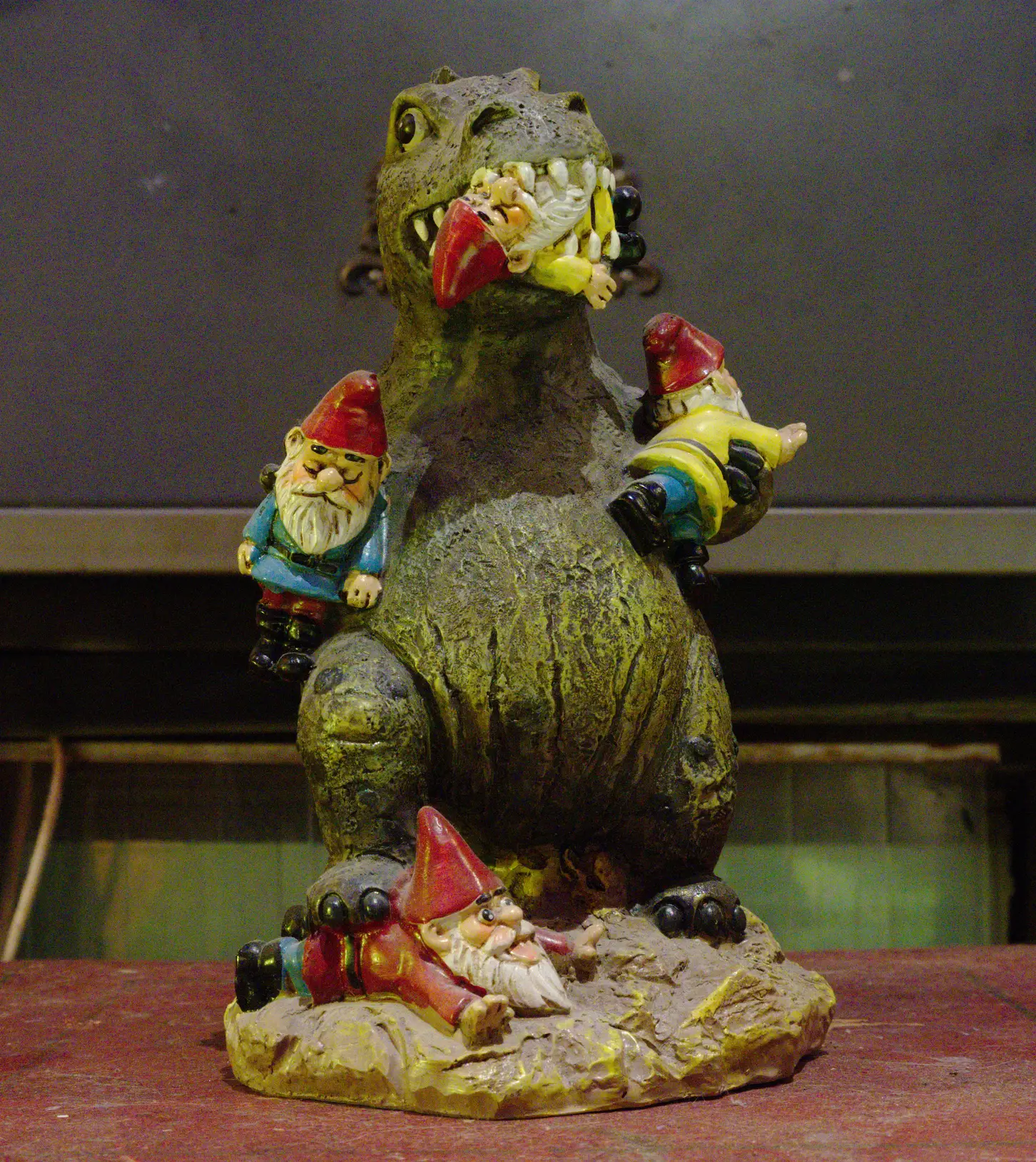 statue on a table of a green monster consuming gnomes